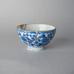 Second side view of an Edo-period Ko-Imari sake cup, its karakusa vine pattern crossed by fine 24K gold kintsugi lines in natural urushi lacquer.