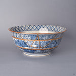 Front view of a Kyoto ware porcelain serving bowl in hand-painted sometsuke blue, a branching 24K gold kintsugi seam descending from rim through lattice and landscape bands.