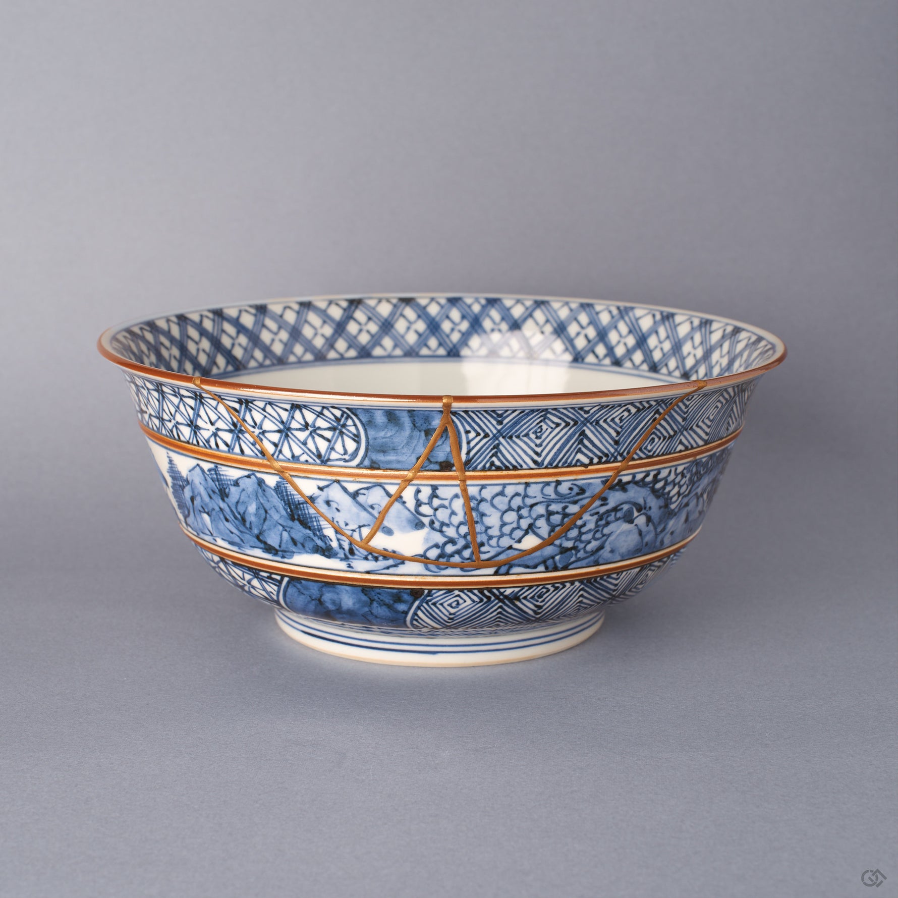 Front view of a Kyoto ware porcelain serving bowl in hand-painted sometsuke blue, a branching 24K gold kintsugi seam descending from rim through lattice and landscape bands.