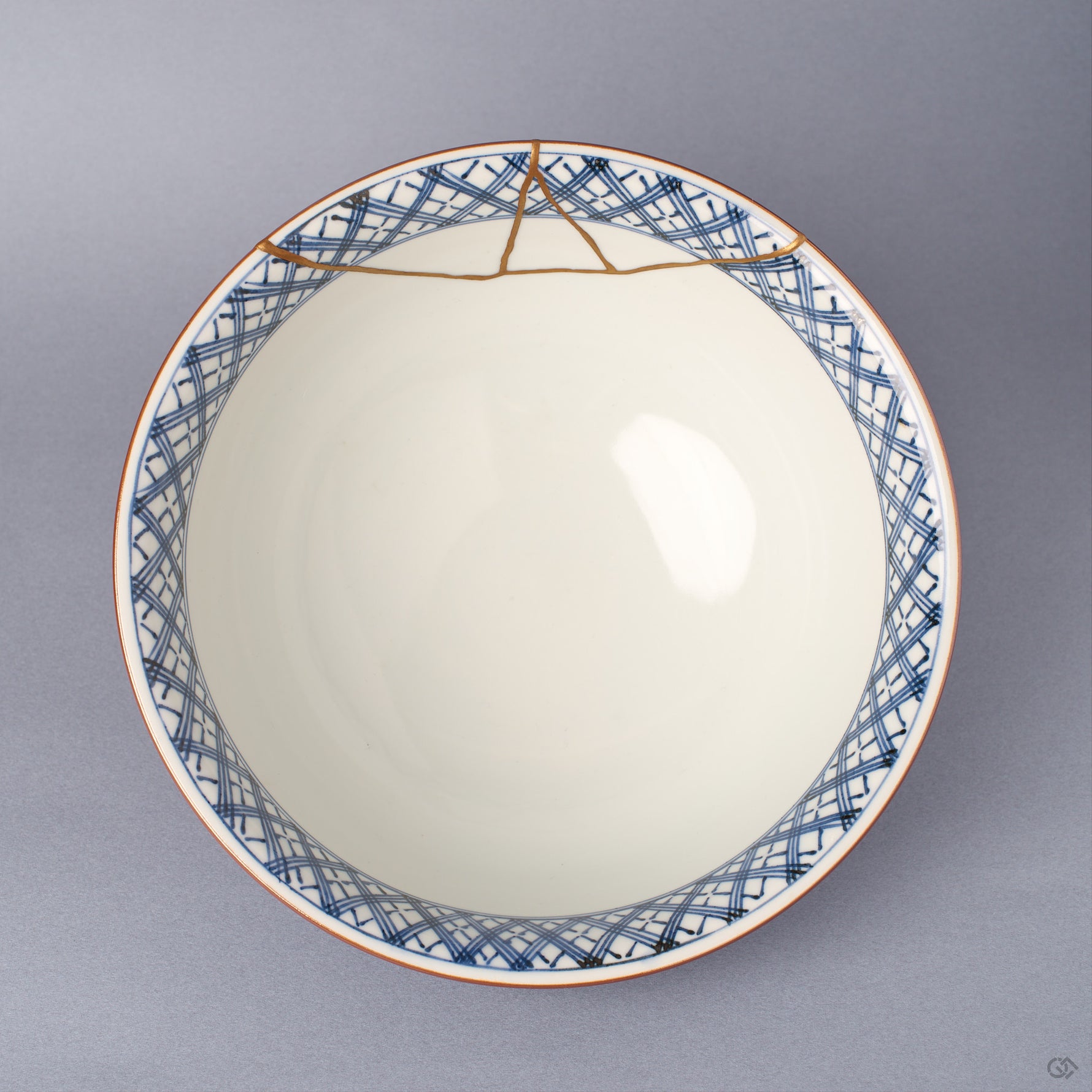 Top view of the Kyoto ware kintsugi serving bowl showing the white interior, the hand-painted blue lattice rim band, and the gold seam crossing the rim edge.