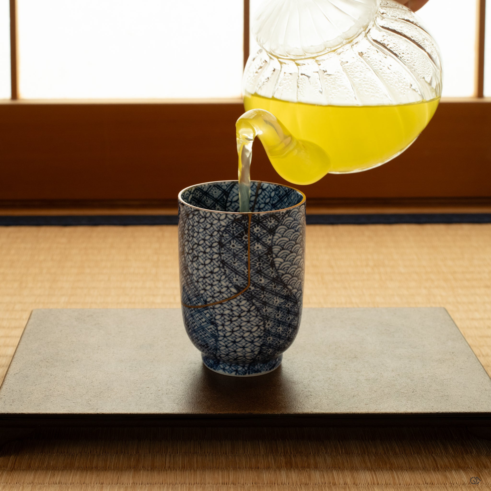 Kintsugi tea cup on tatami in soft natural light, restored with gold and resting in a moment of contemplation.