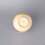 Bottom view of the cream colored Kyoto ware kintsugi cup, showing the small trimmed foot ring of the earthenware vessel restored with natural urushi and 24K gold.