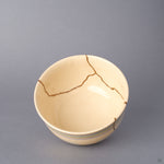Interior close-up of the Kyoto ware kintsugi cup, showing the cream glaze, fine crackle, and a 24K gold seam crossing the inner rim where the earthenware was restored.