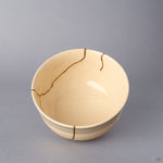 Close-up inside the cream colored Kyoto ware kintsugi cup, detailing the soft crackle glaze and the gold-finished seams of the natural urushi restoration in 24K gold.
