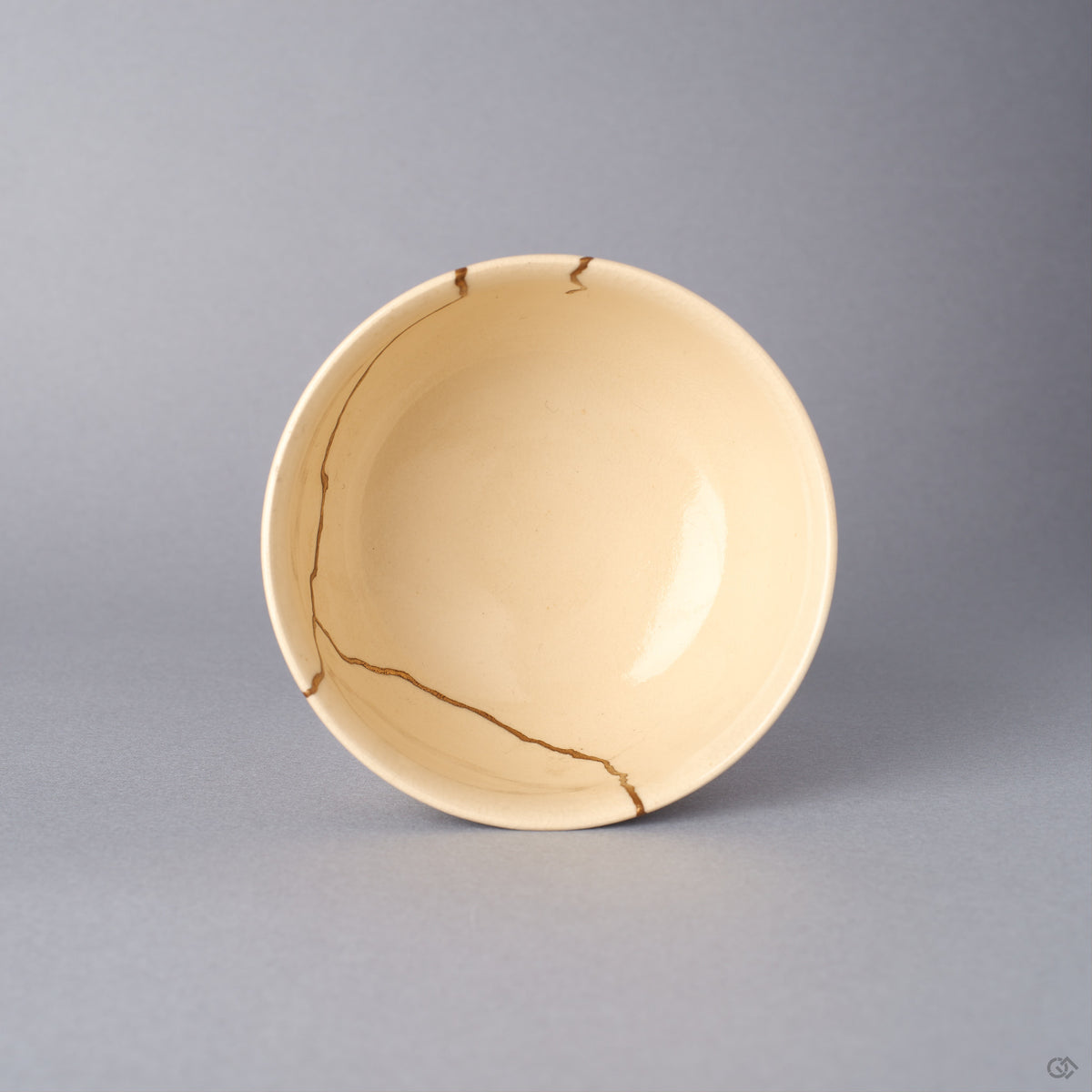 Top-down view of the Kyoto ware kintsugi cup, the round rim banded with koma-suji lines in blue, green, and gold and the interior seams finished in 24K gold urushi.