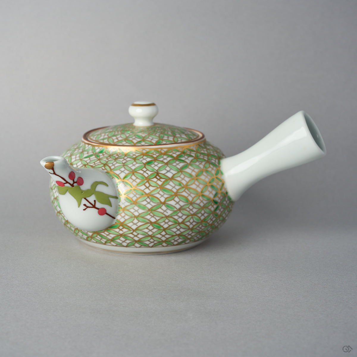 Front view of a Kyoto ware kintsugi teapot with a side handle, gold and green shippo pattern over white porcelain, and a nandina branch in urushi-e on the spout finished in 24K gold.