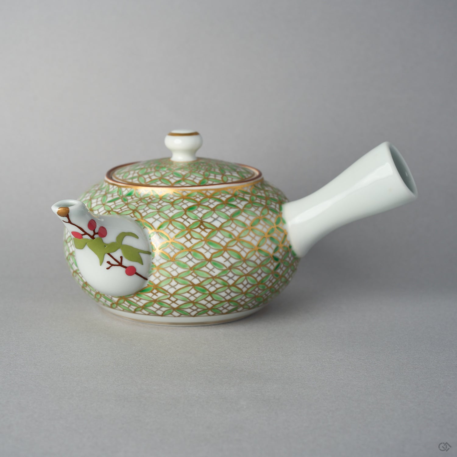 Front view of a Kyoto ware kintsugi teapot with a side handle, gold and green shippo pattern over white porcelain, and a nandina branch in urushi-e on the spout finished in 24K gold.