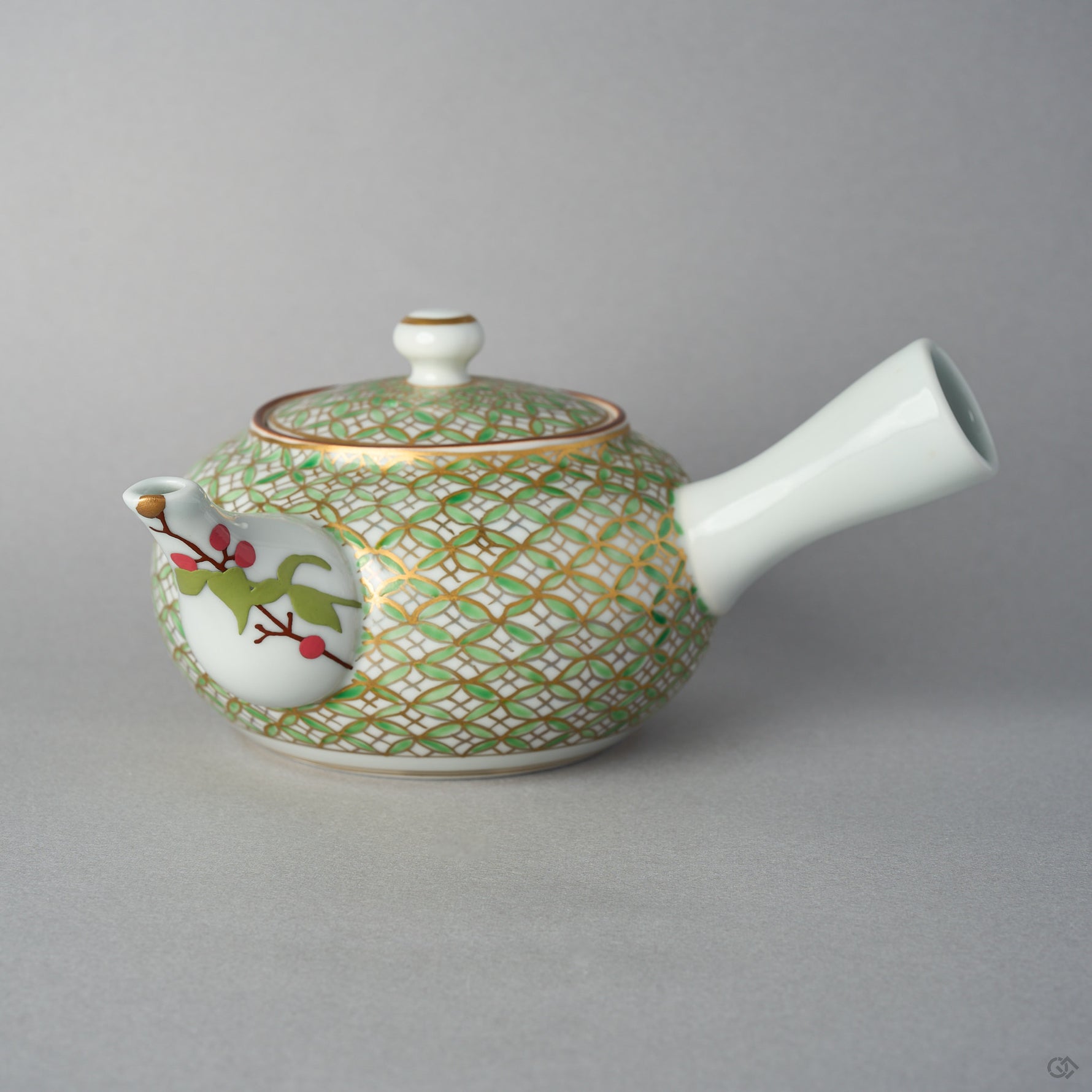 Front view of a Kyoto ware kintsugi teapot with a side handle, gold and green shippo pattern over white porcelain, and a nandina branch in urushi-e on the spout finished in 24K gold.