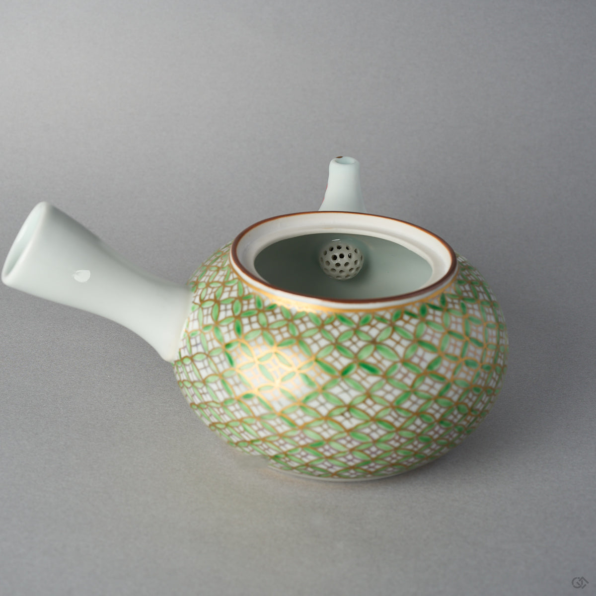 Side view of the Kyoto ware kintsugi teapot showing the white side handle, the gilded shippo lattice in green enamel, and the nandina-painted spout tipped in 24K gold.