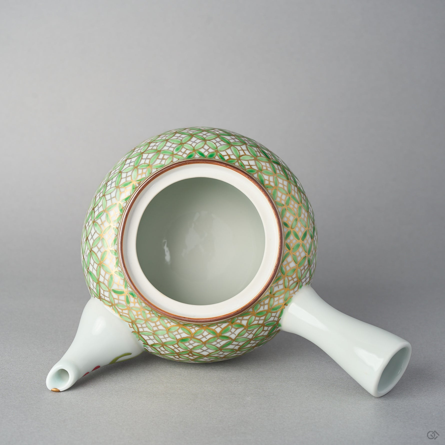 Top view of the open Kyoto ware teapot body without its lid, showing the ceramic mesh strainer inside, the brown-lined rim, and the gilded shippo pattern in green enamel.