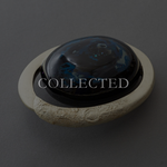 Union of Skies, Japanese urushi lacquer art object by Keiko Hata: a glossy black dome with blue and white cloud-like patterns set in a pale textured ring, front angle. Collected.